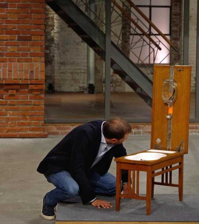 Julian Schmitz-Avila begutachtet ein antikes Klapp-Bidet.