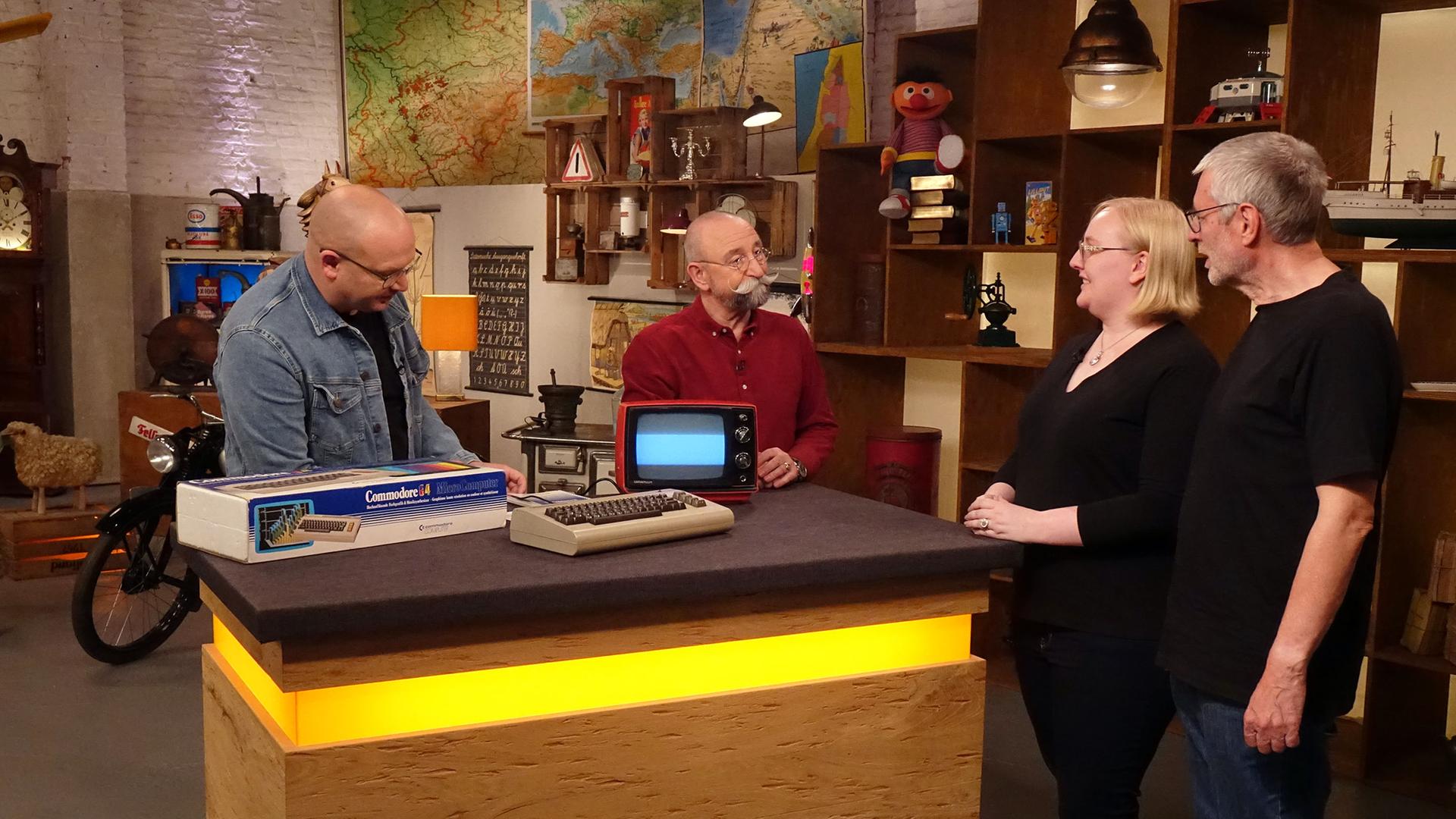 Experte Sven Deutschmanek begutachtet einen "C64" von Commodore. Neben ihm am Expertentisch stehen Horst Lichter, die Verkäuferin und der Verkäufer.
