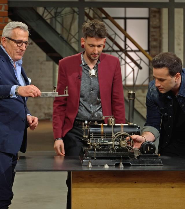 Markus Wildhagen, Fabian Kahl und David Suppes begutachten eine alte Dampfmaschine von Märklin.