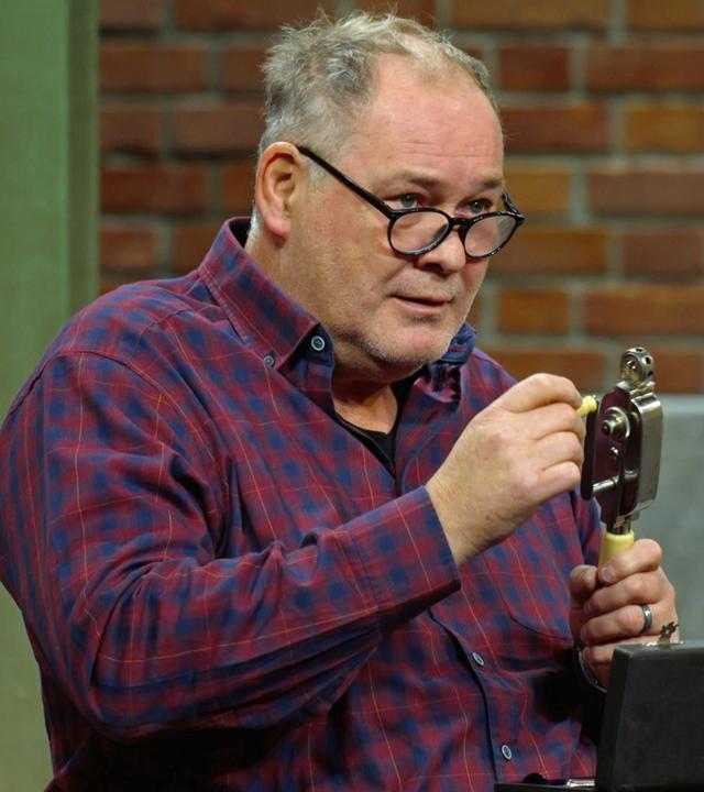 Walter Lehnertz begutachtet ein altes Handkurbelmassagegerät aus dem Jahr 1920.