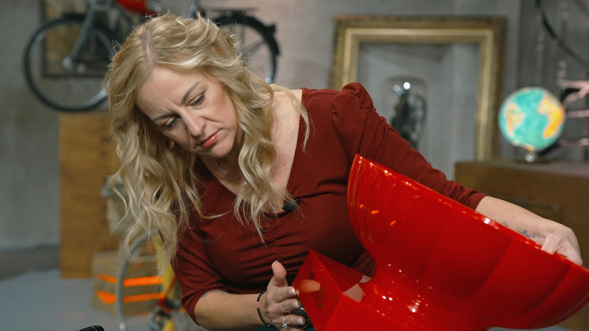 Annika Raßbach begutachtet einen roten Champagnerkühler von Piper-Heidsieck.