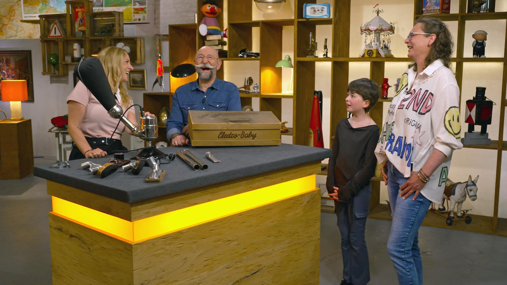 Horst Lichter, eine Expertin und die verkäufer eines Multifunktions-Gerätes amüsieren sich im Expertisenraum. 