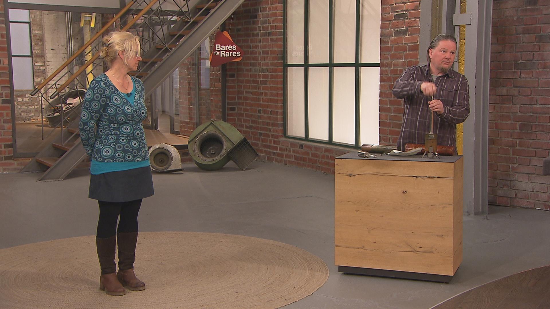 Ein Verkäufer-Ehepaar zeigt im Händlerraum, wie ihr Verkaufsobjekt, ein Hypsometer, zusammengebaut wird.