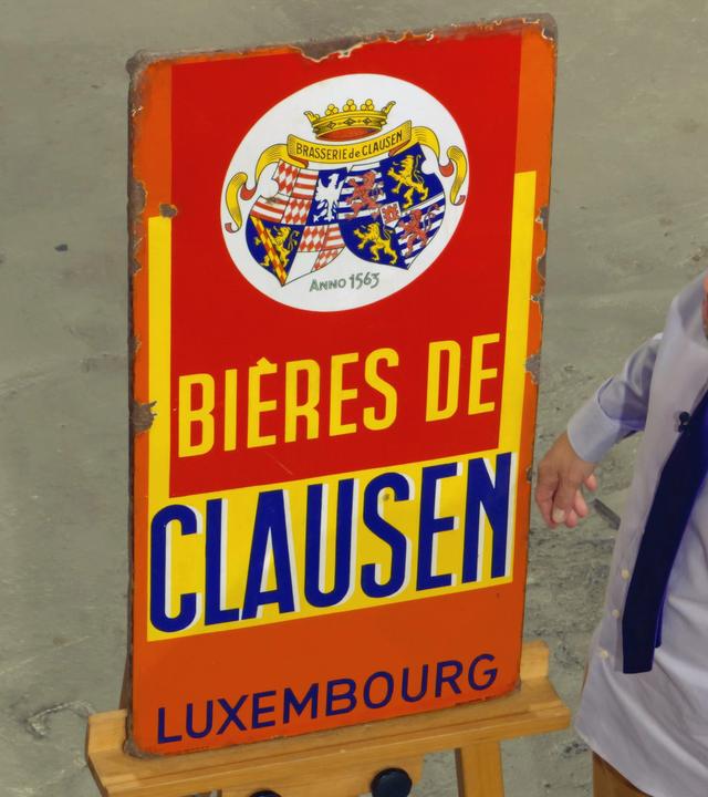 Wolfgang Pauritsch steht neben einem Werbeschild der Biermarke Clausen.