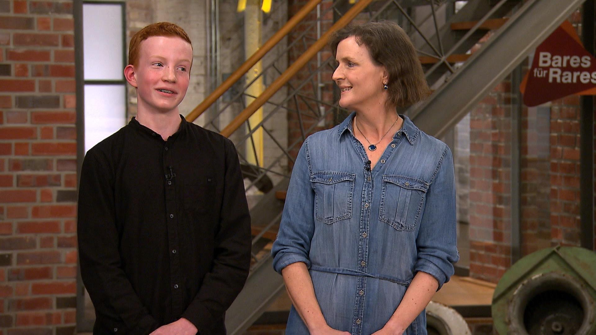 Mutter und Sohn stehen im Walzwerk vor einer Treppe.