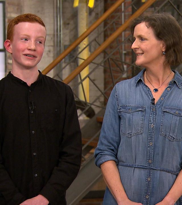 Mutter und Sohn stehen im Walzwerk vor einer Treppe.