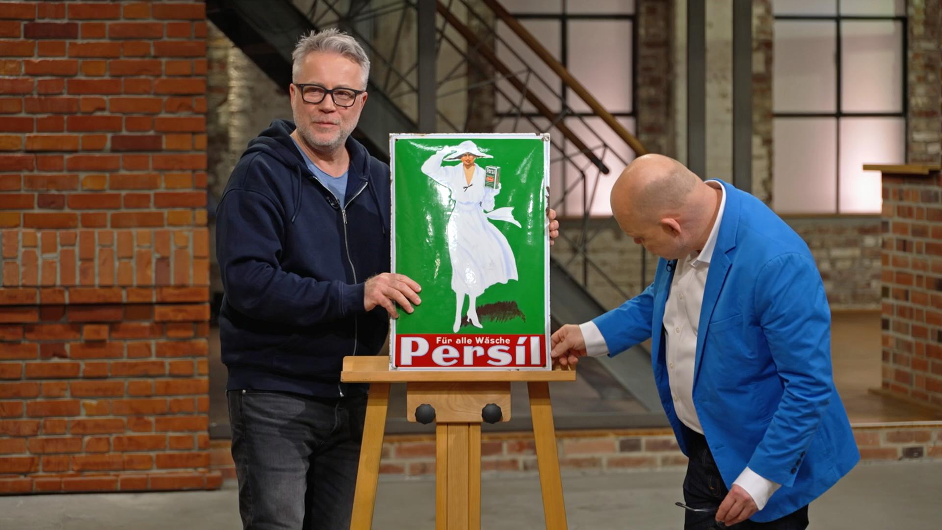 Jan Cizek und Benjamin Leo Leo begutachten ein Werbeschild von Persil aus den 1920er-Jahren.