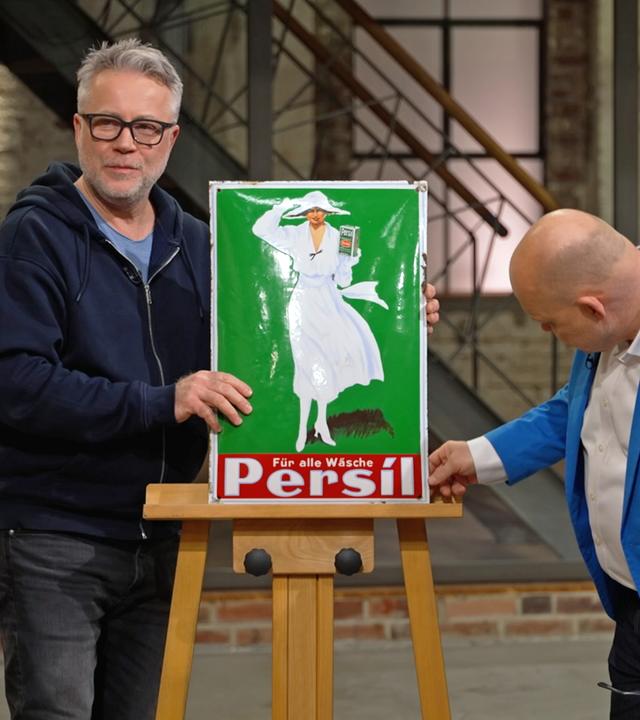Jan Cizek und Benjamin Leo Leo begutachten ein Werbeschild von Persil aus den 1920er-Jahren.