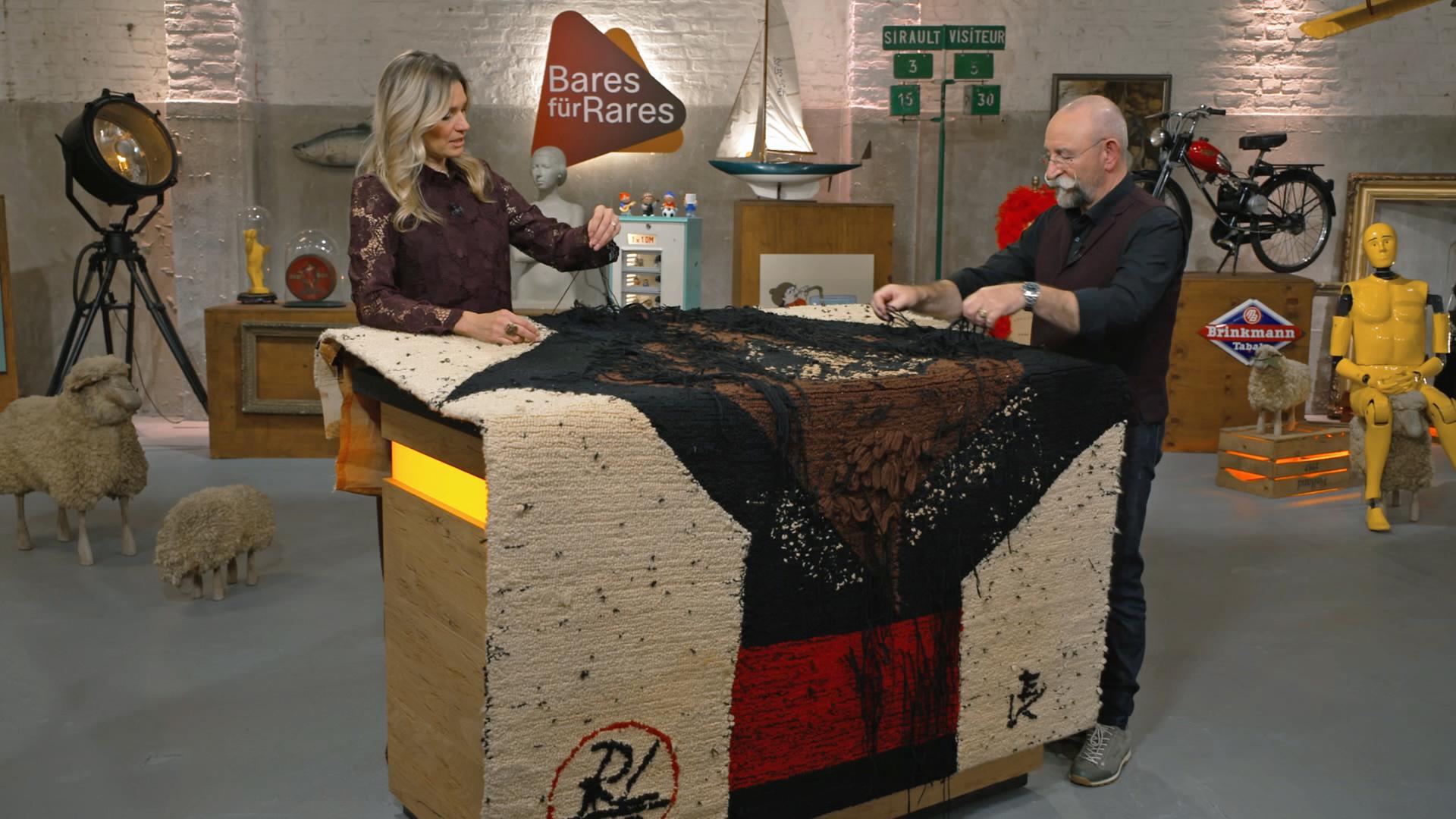 Bianca Berding und Horst Lichter begutachten einen Wandteppich von Rolf Otto Lehmann.