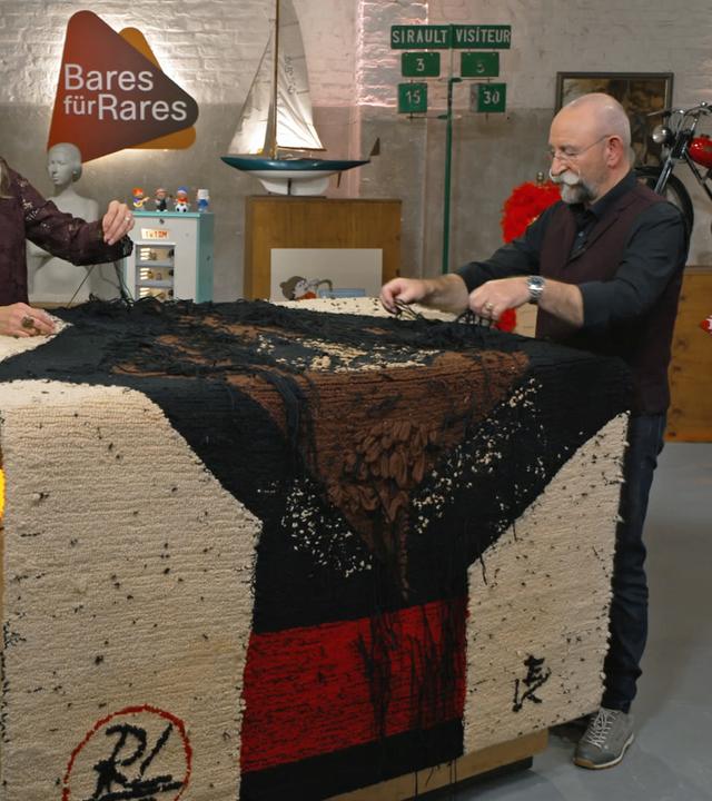 Bianca Berding und Horst Lichter begutachten einen Wandteppich von Rolf Otto Lehmann.