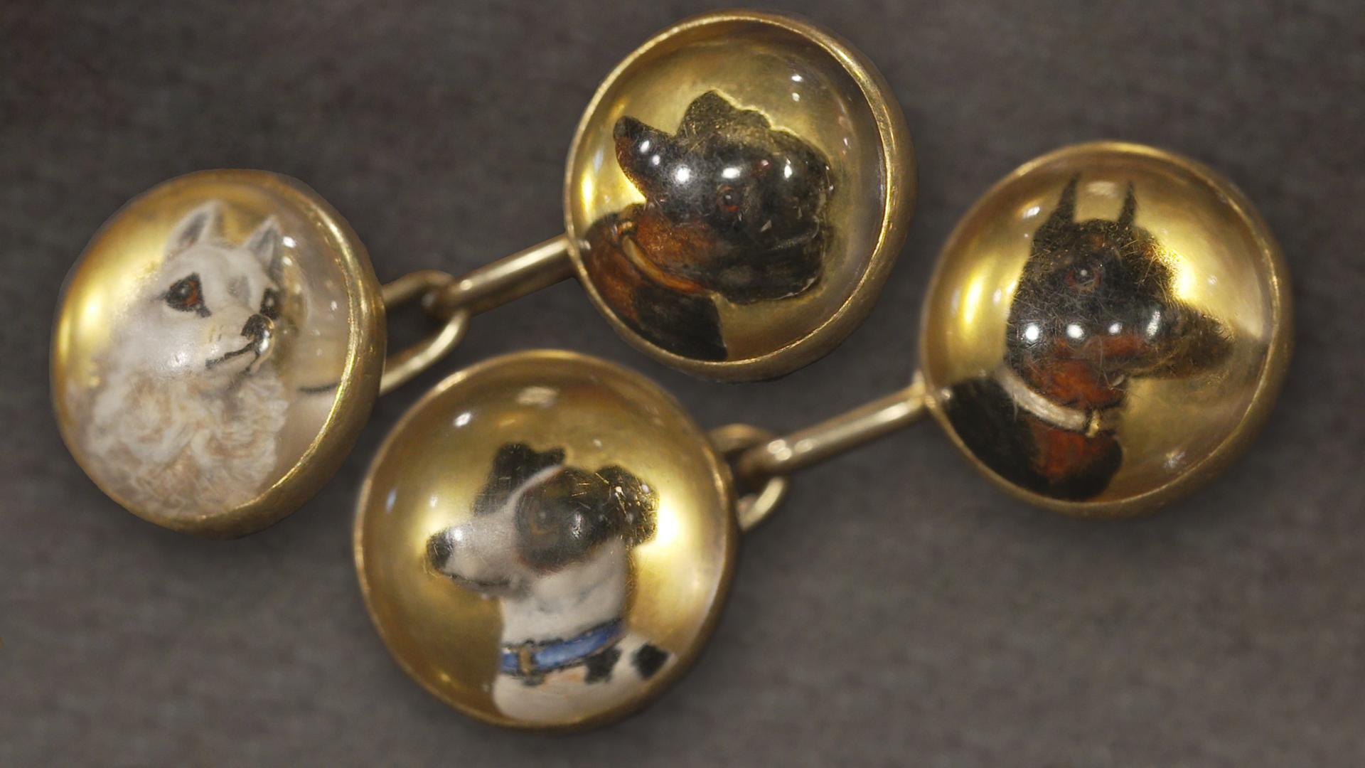 Antike Manschettenknöpfe mit unterschiedlichen Hunderassen verziert.