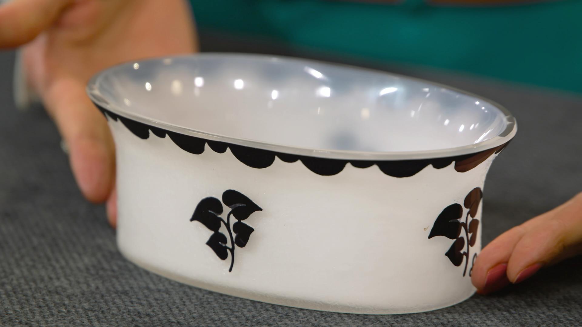 Weißes Glasschälchen mit schwarzen Verzierungen.