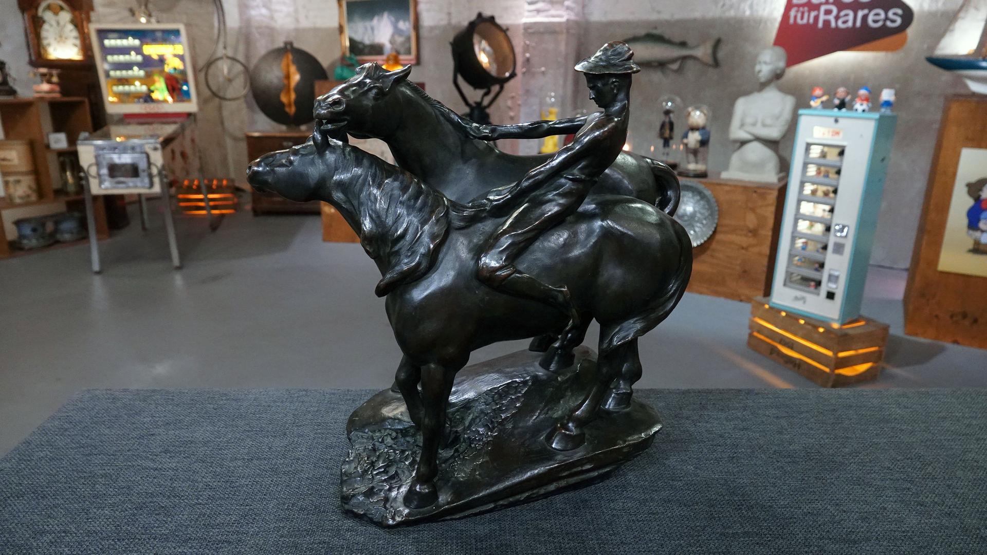 Eine Bronzeskulptur von Leonhard Zeiher zeigt zwei galoppierende Pferde und einen Reiter