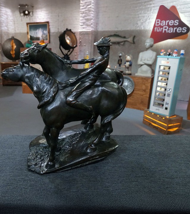 Eine Bronzeskulptur von Leonhard Zeiher zeigt zwei galoppierende Pferde und einen Reiter