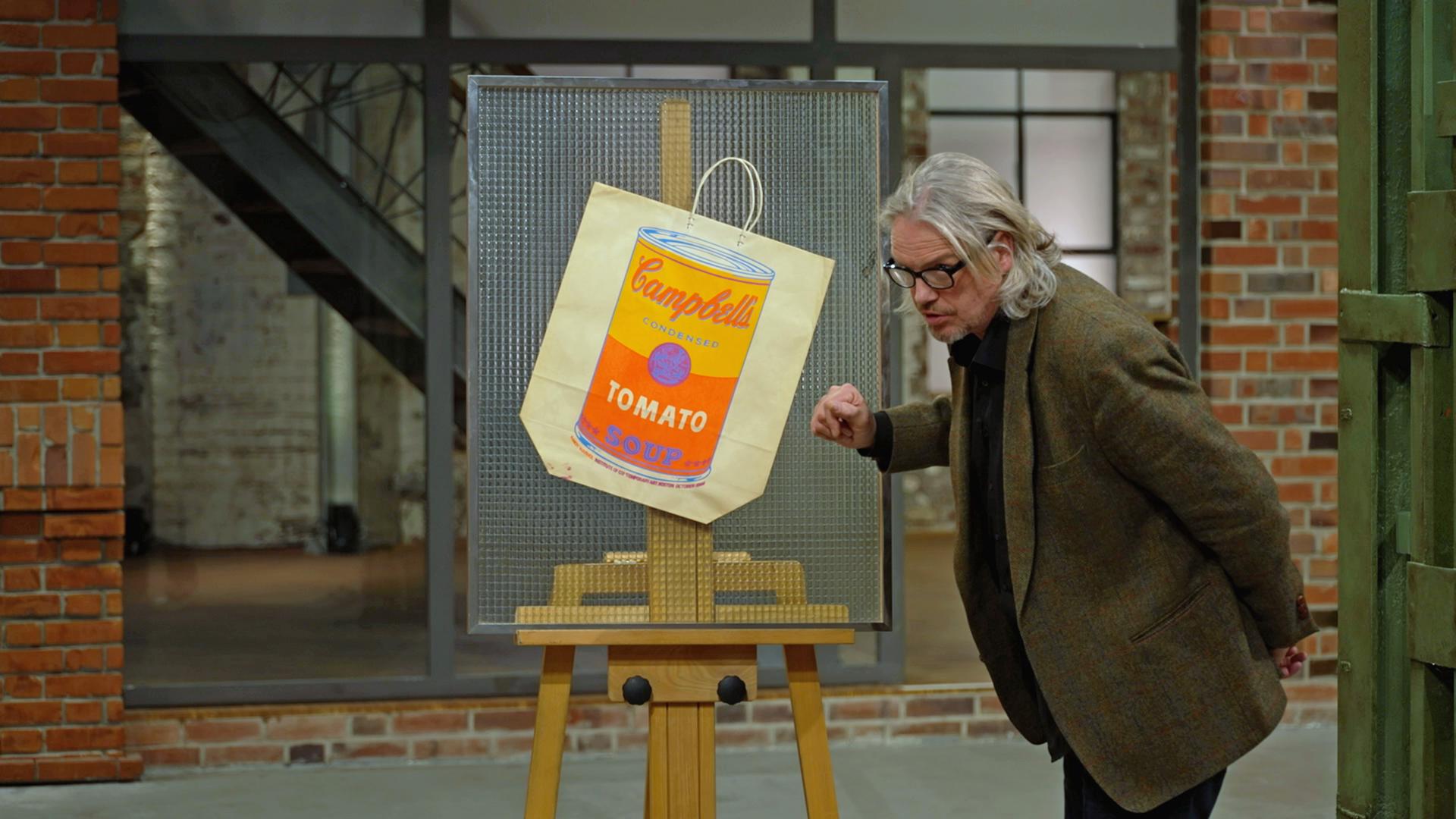Jos van Katwijk begutachtet einen Farbsiebdruck auf Papiertragetasche von Andy Warhol. 