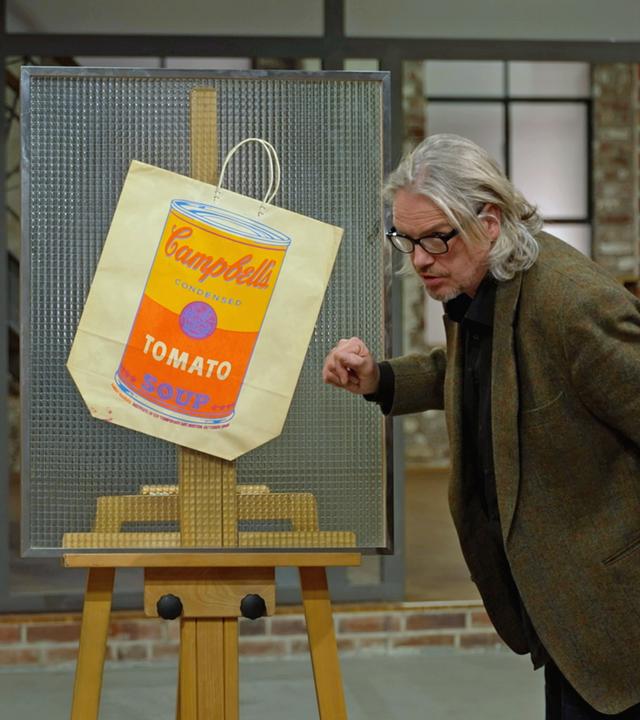 Jos van Katwijk begutachtet einen Farbsiebdruck auf Papiertragetasche von Andy Warhol. 