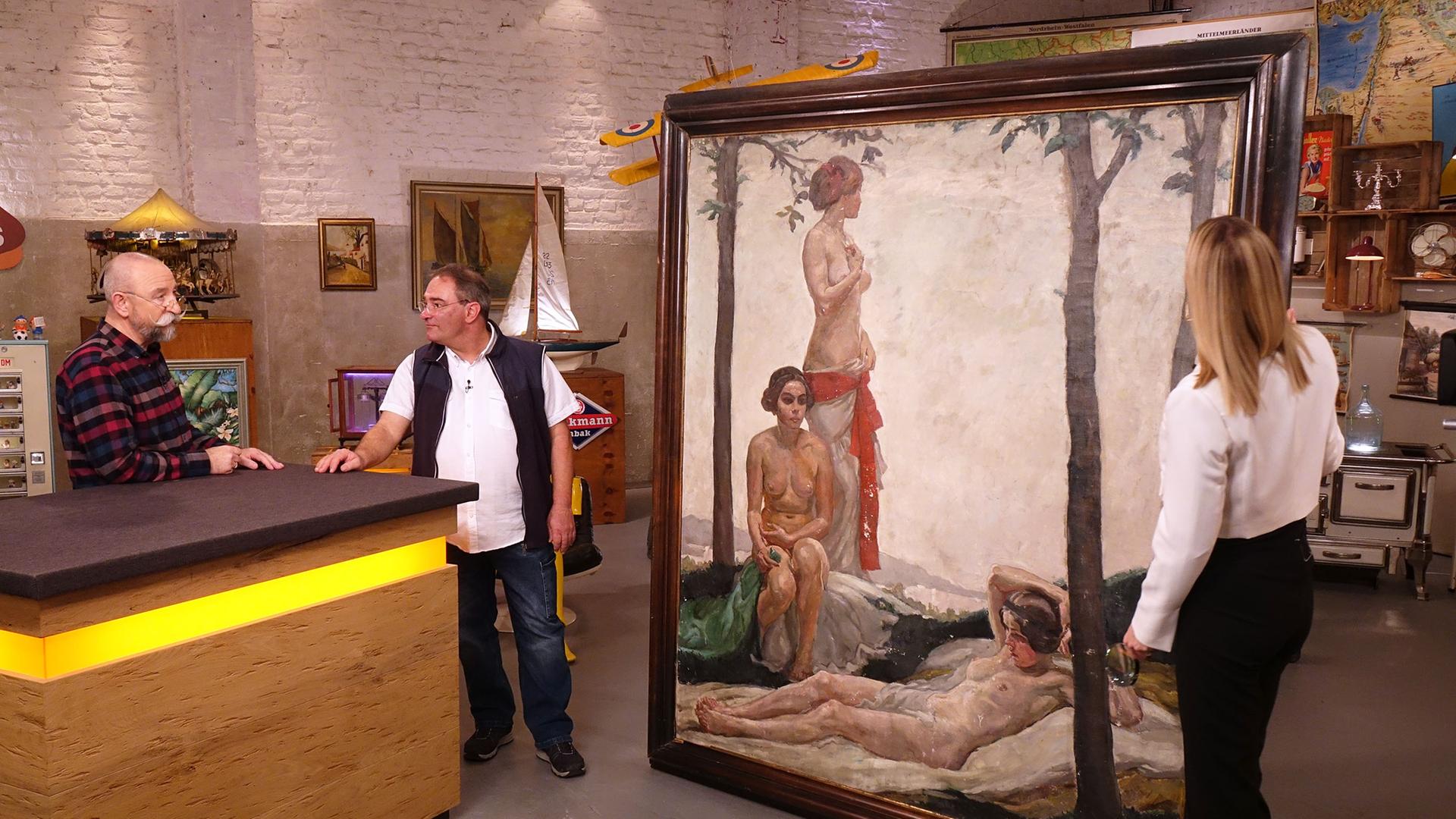 Expertin Dr. Bianca Berding begutachtet ein überdimensionales Gemälde von Max Beringer. Am Expertisentisch stehen Horst Lichter und der Verkäufer des Gemäldes.