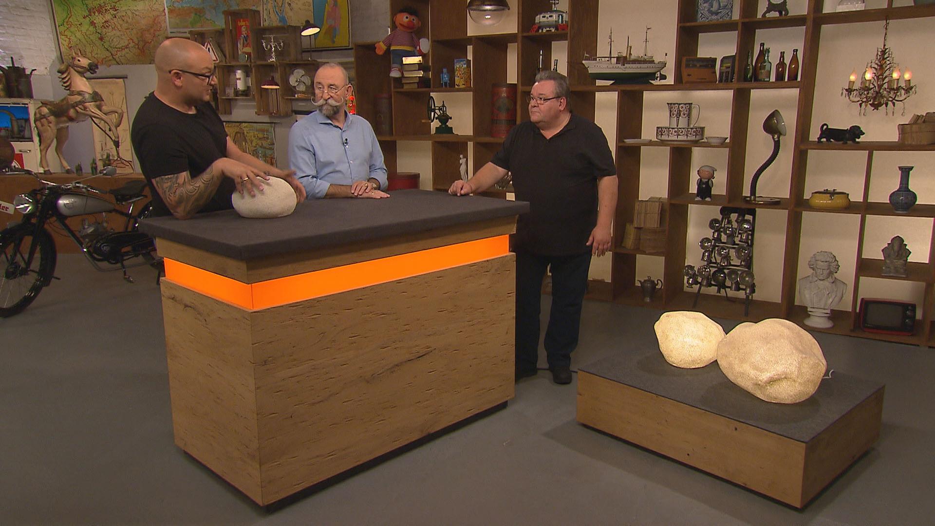 Experte Sven Deutschmanek begutachtet Leuchtsteine von Singleton. Neben ihm am Expertisentisch stehen Horst Lichter und der Verkäufer.