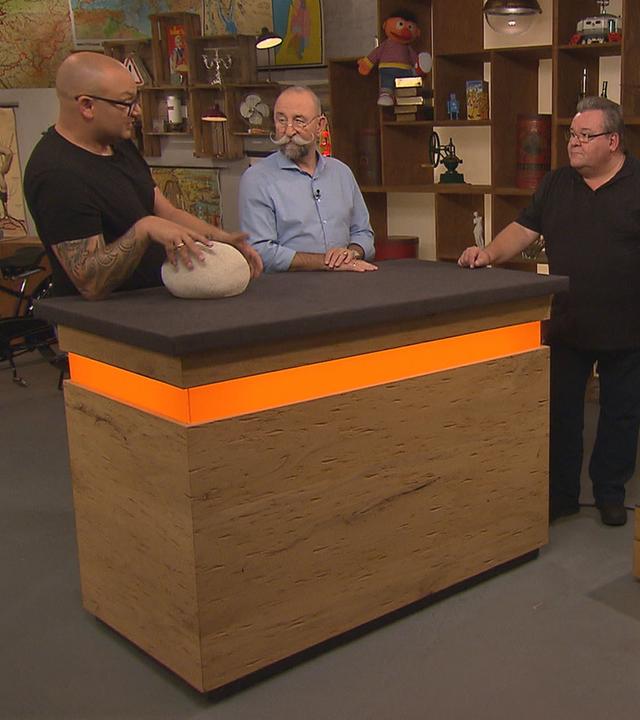 Experte Sven Deutschmanek begutachtet Leuchtsteine von Singleton. Neben ihm am Expertisentisch stehen Horst Lichter und der Verkäufer.