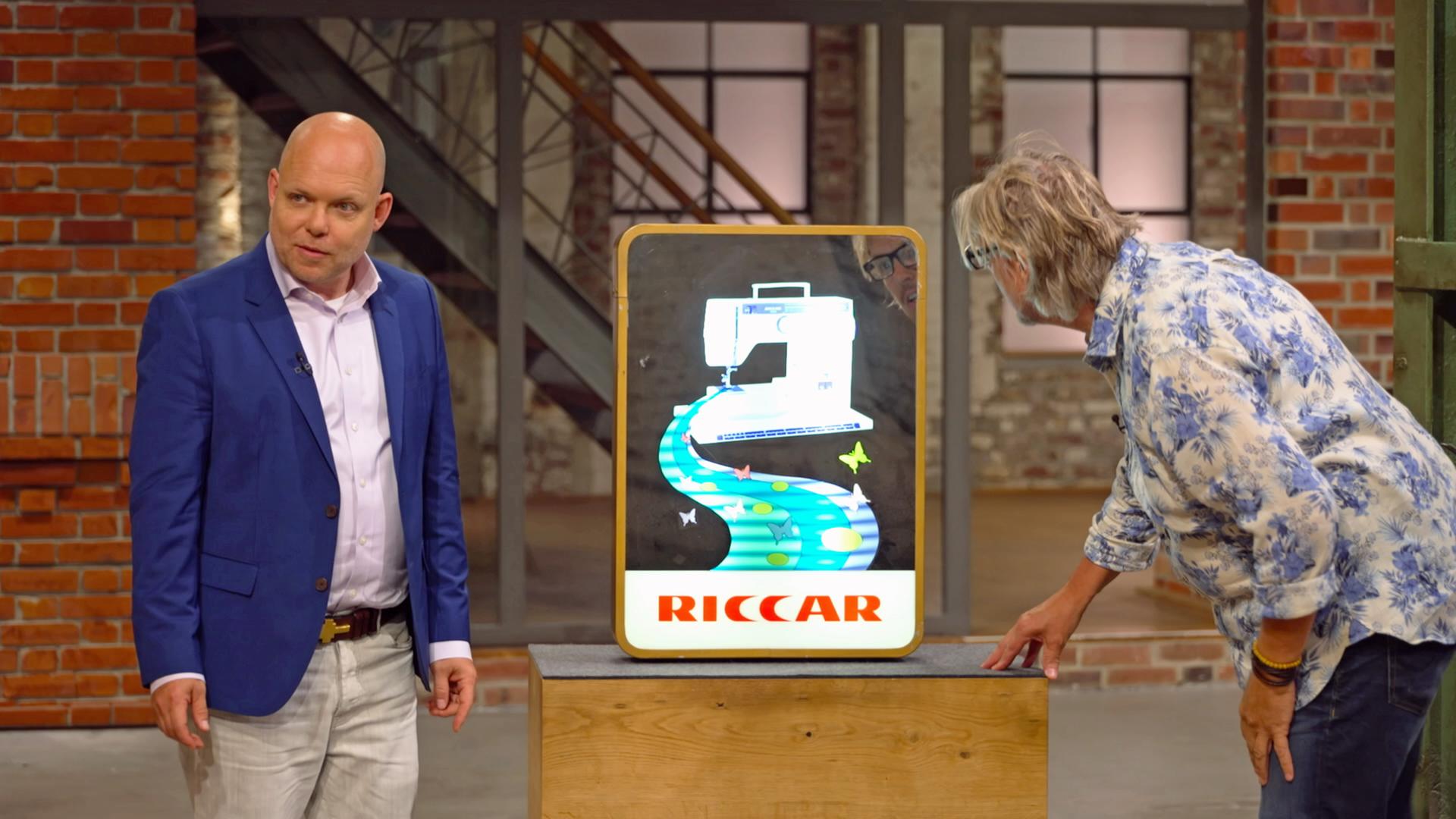 Benjamin Leo Leo und Jos van Katwijk begutachten ein altes Leuchtreklameschild für eine Riccar-Nähmaschine.
