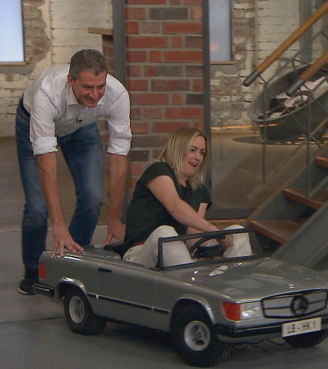 Der Verkäufer eines Mercedes SL 500 Mini schiebt das Auto in den Händlerraum. Hinterm Steuer des Wagens sitzt die Verkäuferin.