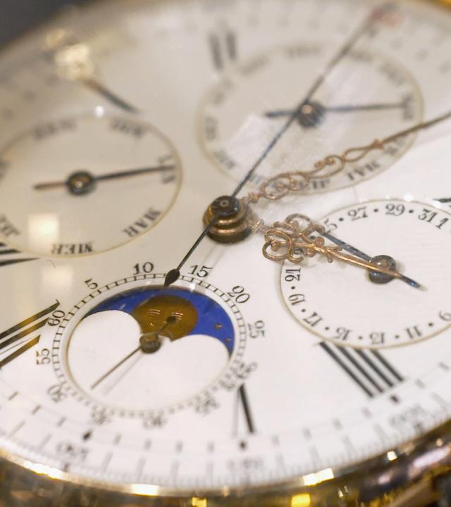 Schweizer Taschenuhr mit goldenem Gehäuse und weißem Ziffernblatt.