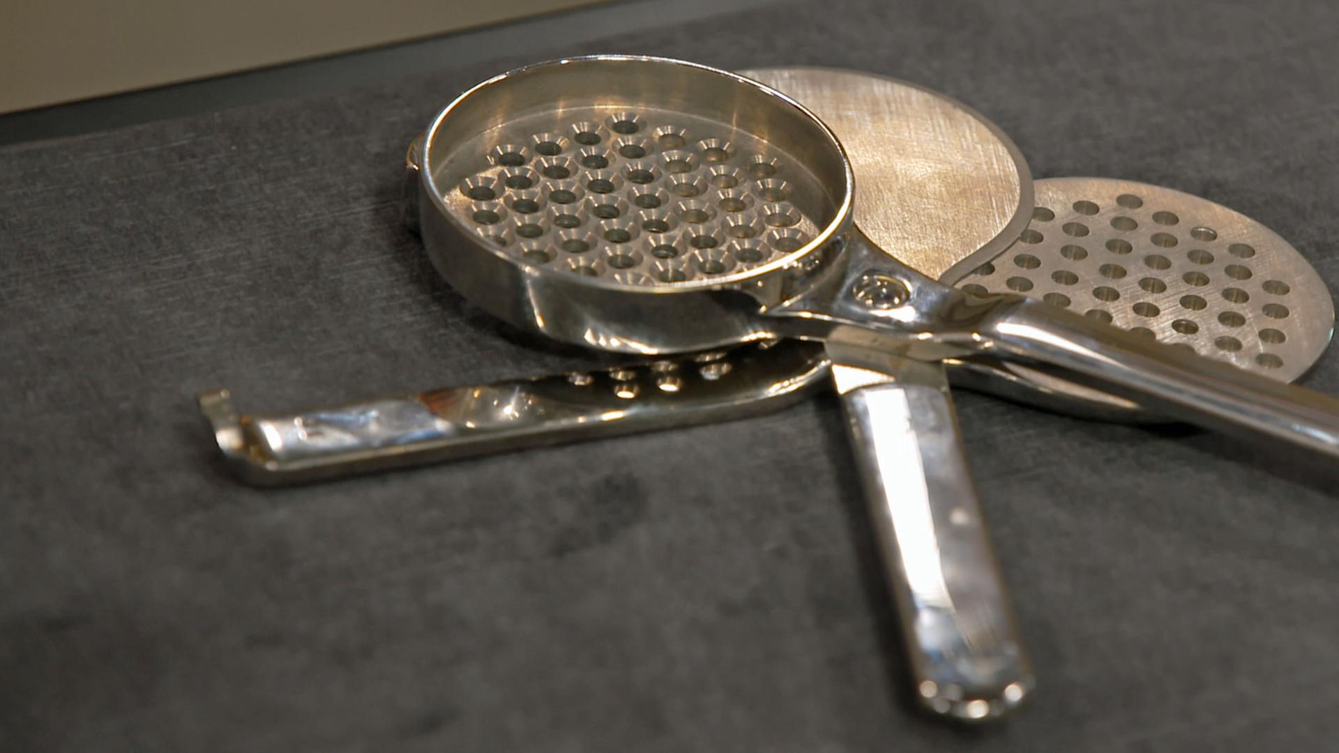 Dreiteiliger Kornteiler mit zwei Sieblöffeln.