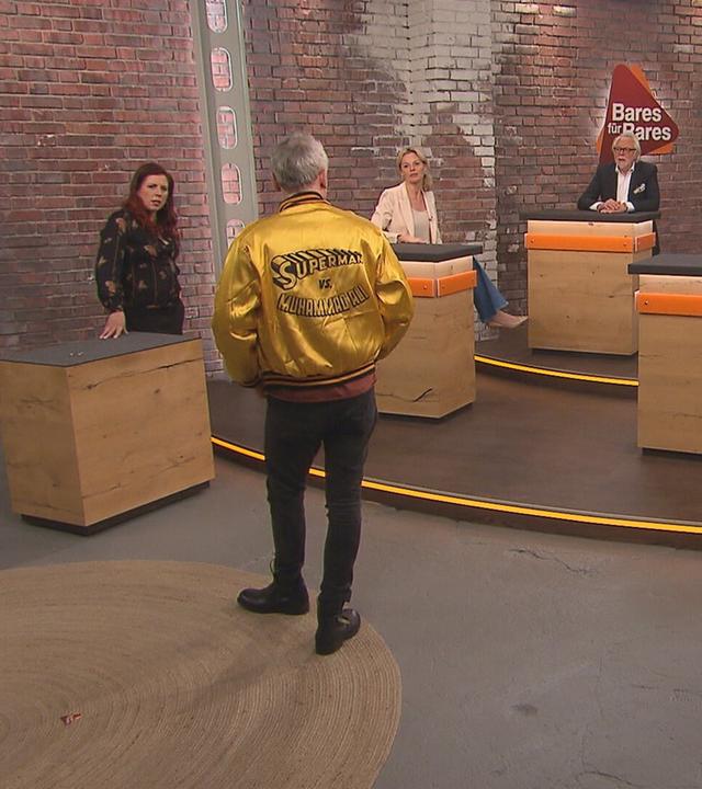 Händler Christian Vechtel posiert im Händlerraum in einer Jacke von Angelo Dundee auf der "Superman vs. Muhammad Ali" aufgedruckt ist