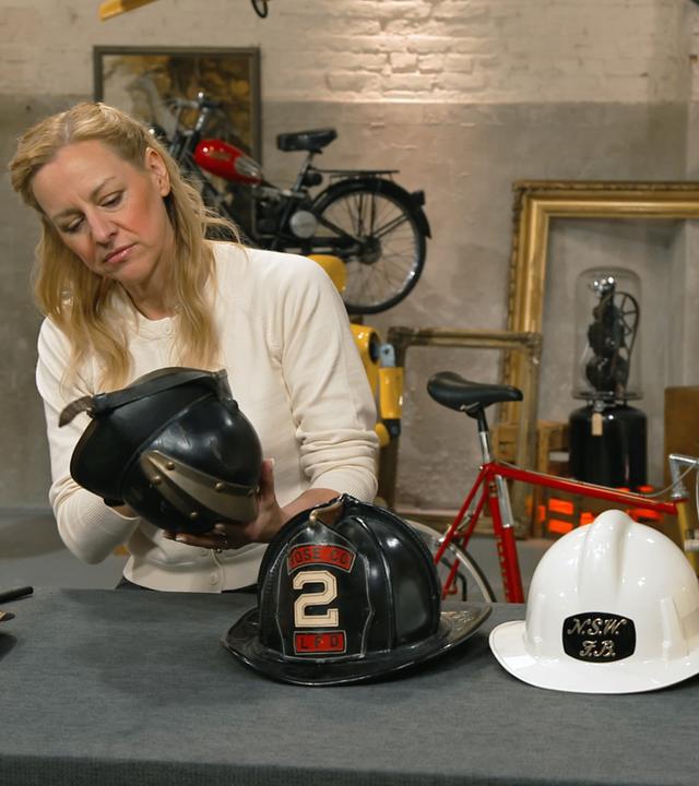 Annika Raßbach begutachtet eine Sammlung internationaler Feuerwehrhelme.
