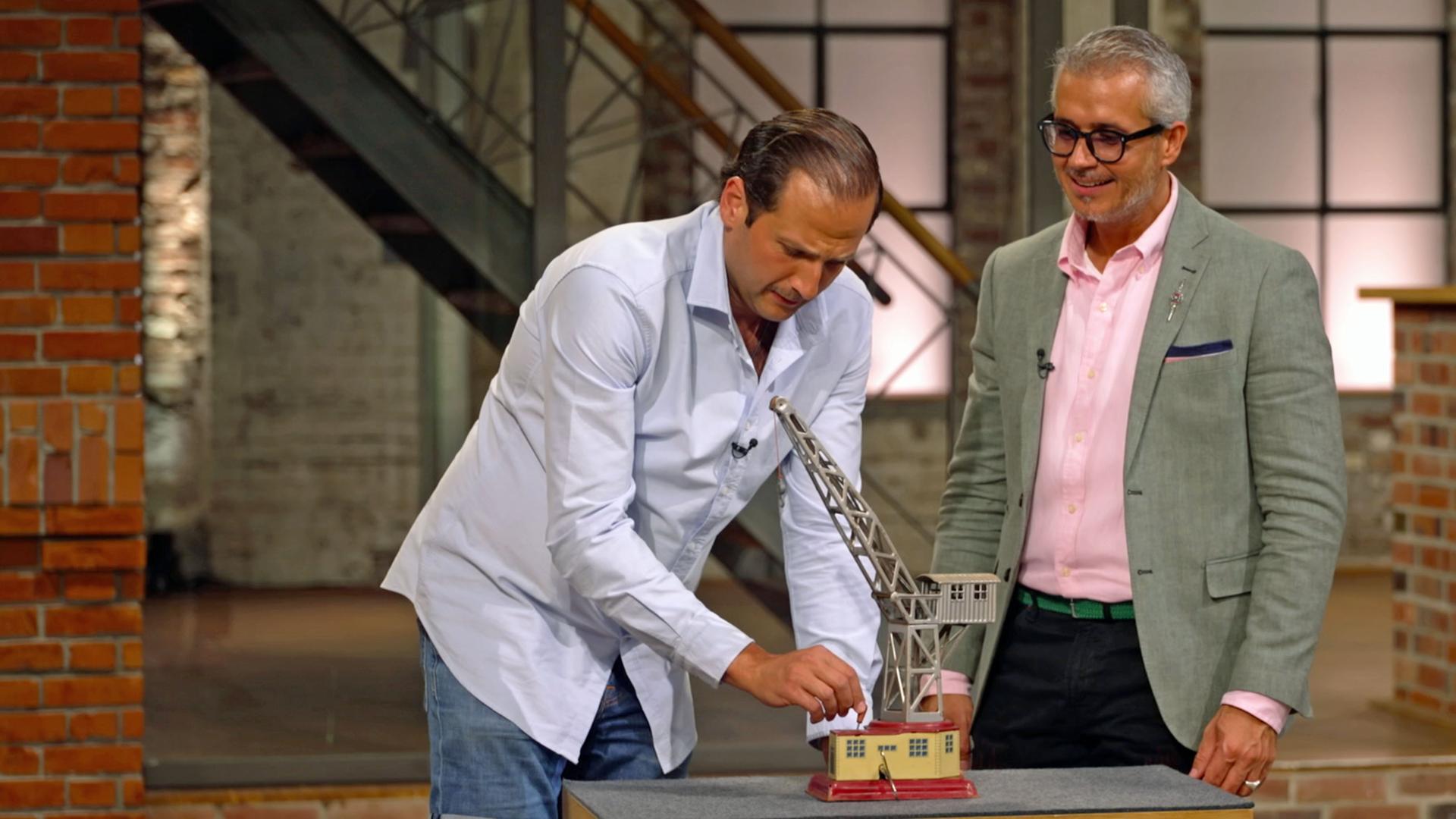 Julian Schmitz-Avila und Anaisio Guedes spielen mit einem kleinen Spielzeug-Kran.