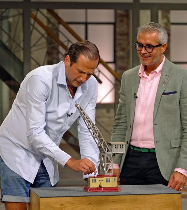 Julian Schmitz-Avila und Anaisio Guedes spielen mit einem kleinen Spielzeug-Kran.