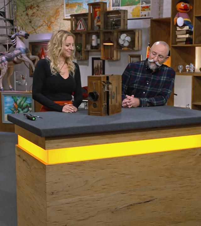 Annika Raßbach und Horst Lichter begutachten eine antike Stummfilmkamera.