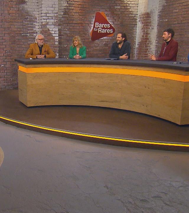 Im Händlerraum steht ein Werbeaufsteller von Boris Becker und daneben der Verkäufer des Aufstellers. Davor sitzt das fünfköpfige Händlerteam.