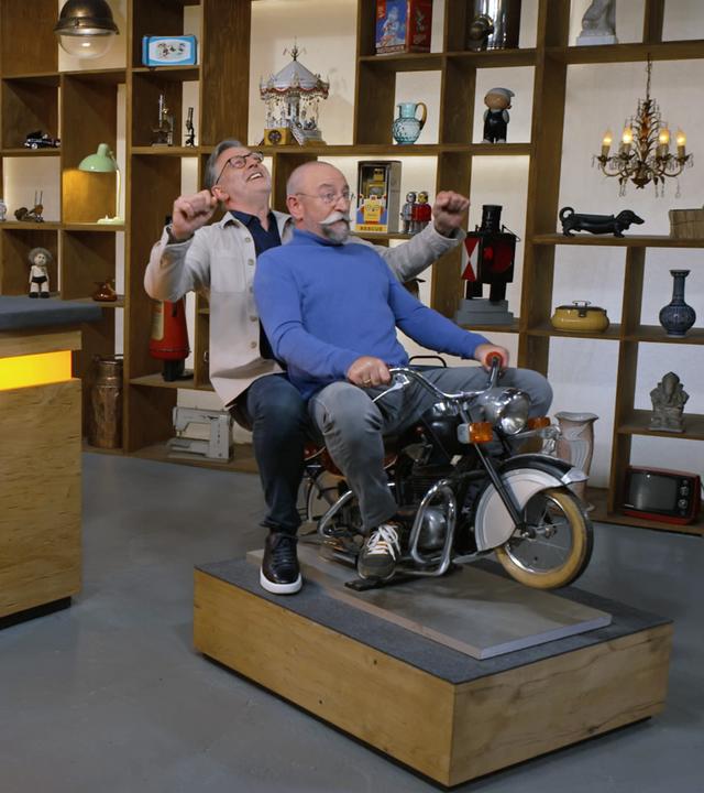 Detlev Kümmler und Horst Lichter sitzen auf einem alten Kinderkarusell-Motorrad.