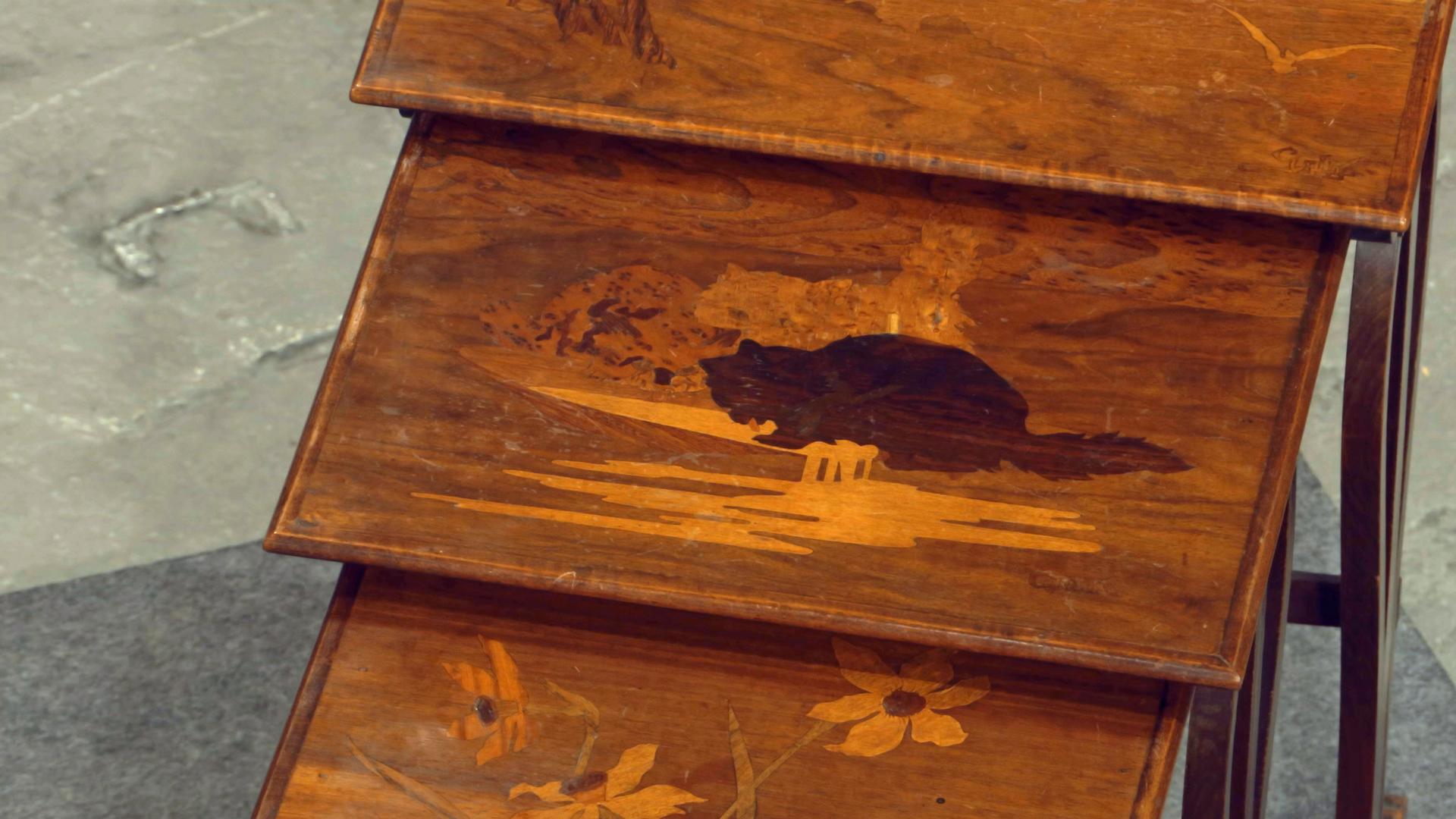 Ein Set aus drei Beistelltischen aus Holz mit verschiedenen Motiven.