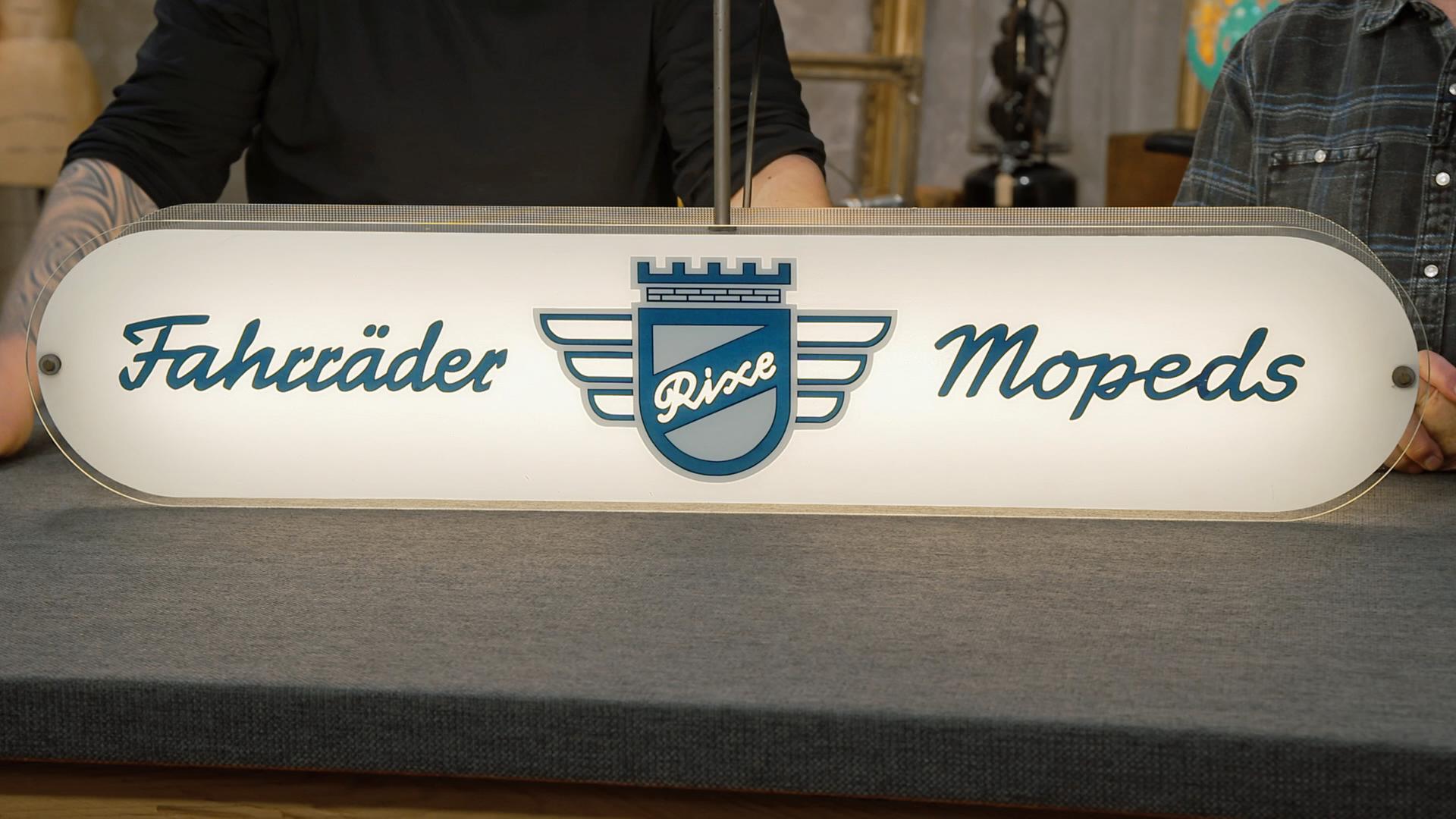Ein leuchtendes Werbeschild für "Rixe" Fahrräder und Mopeds 