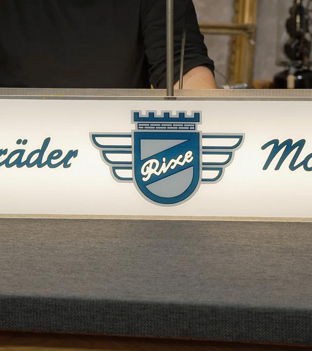 Ein leuchtendes Werbeschild für "Rixe" Fahrräder und Mopeds 