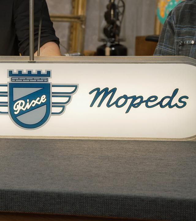 Ein leuchtendes Werbeschild für "Rixe" Fahrräder und Mopeds 