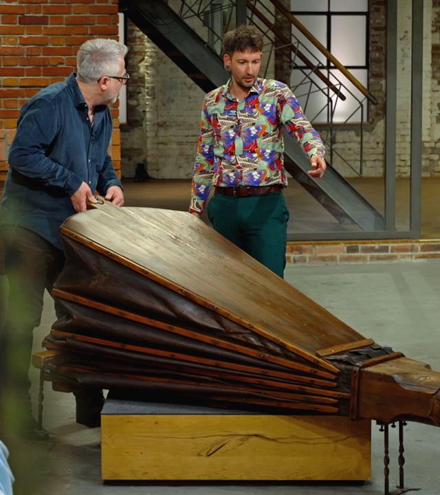 Lisa Nüdling nimmt das kleineste Buch der Welt unter die Lupe, Jan Cizek und Fabian Kahl begutachten einen großen Blasebalg aus einer Schmiede.