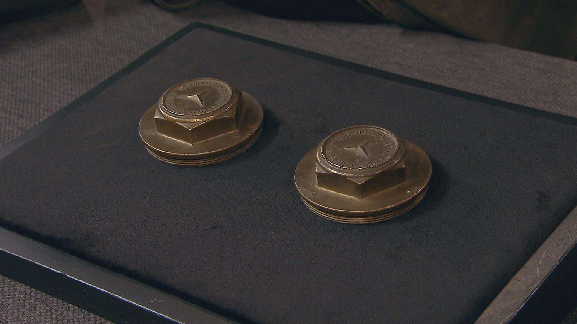 Zwei antike Radnabenkappen liegen auf dem Expertisentisch.