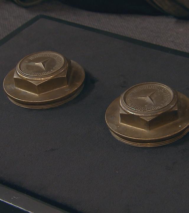 Zwei antike Radnabenkappen liegen auf dem Expertisentisch.