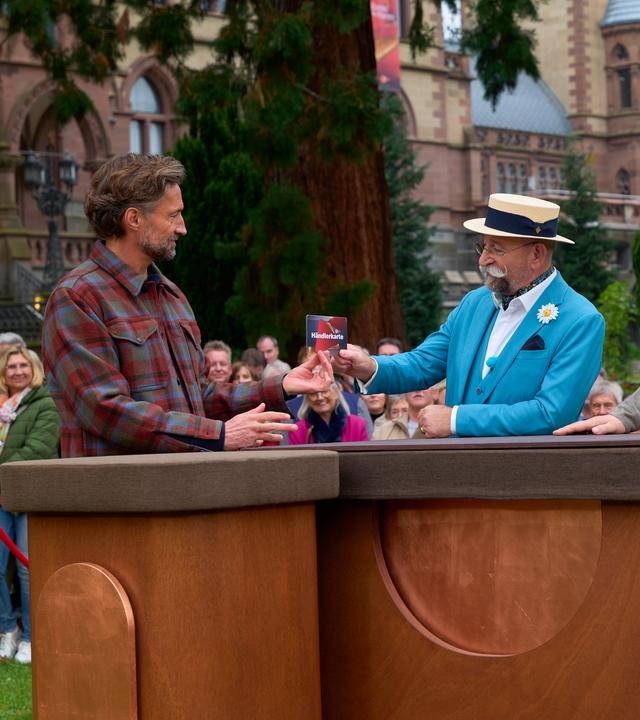 Horst Lichter überreicht Benjamin Sadler die Händlerkarte, daneben steht Sven Deutschmanek.