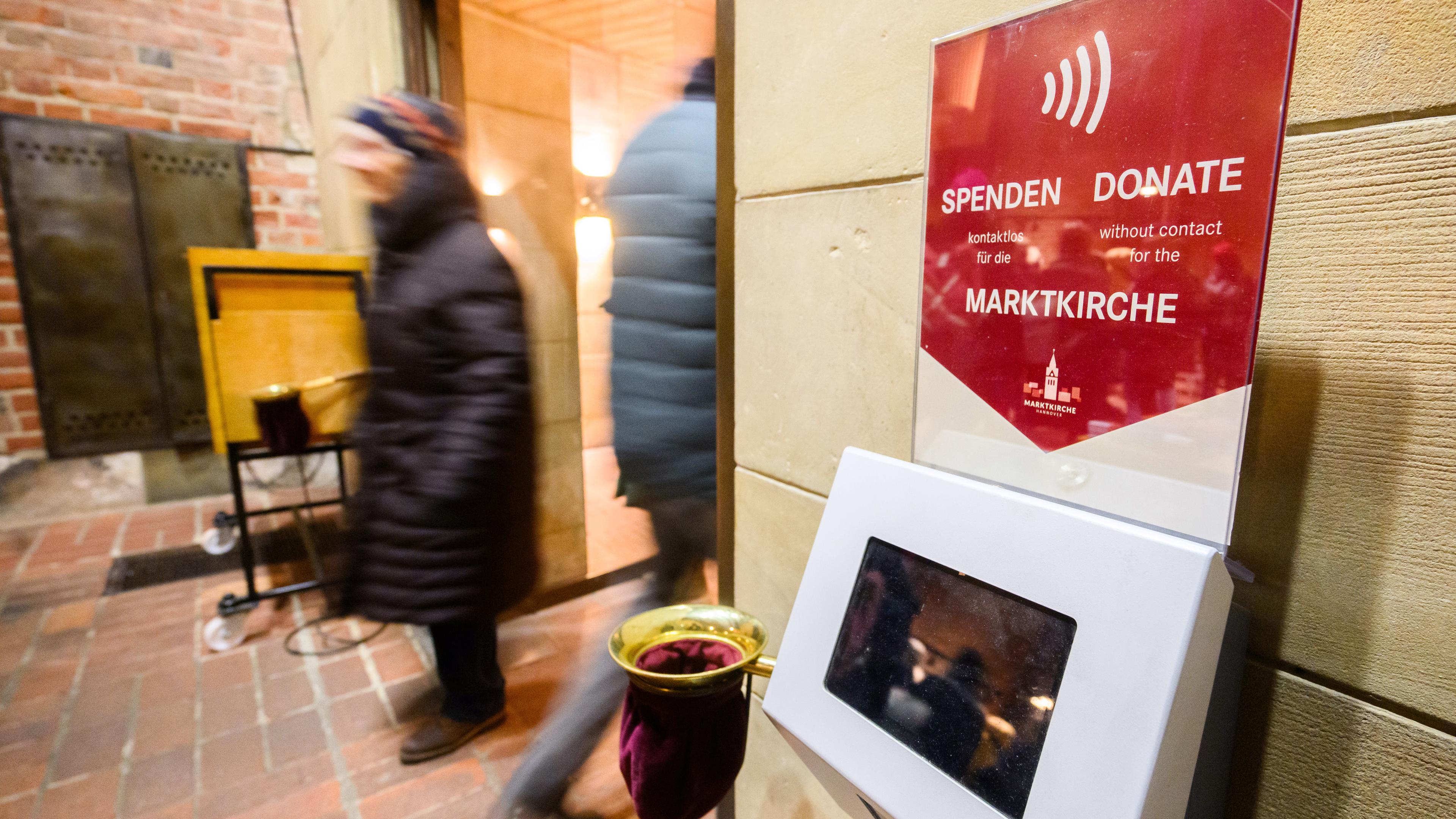 Der sogenannte "Kollektomat" als bargeldlosen Spendenmöglichkeit steht neben einem Klingelbeutel in der Marktkirche in Hannover, aufgenommen am 08.12.2023