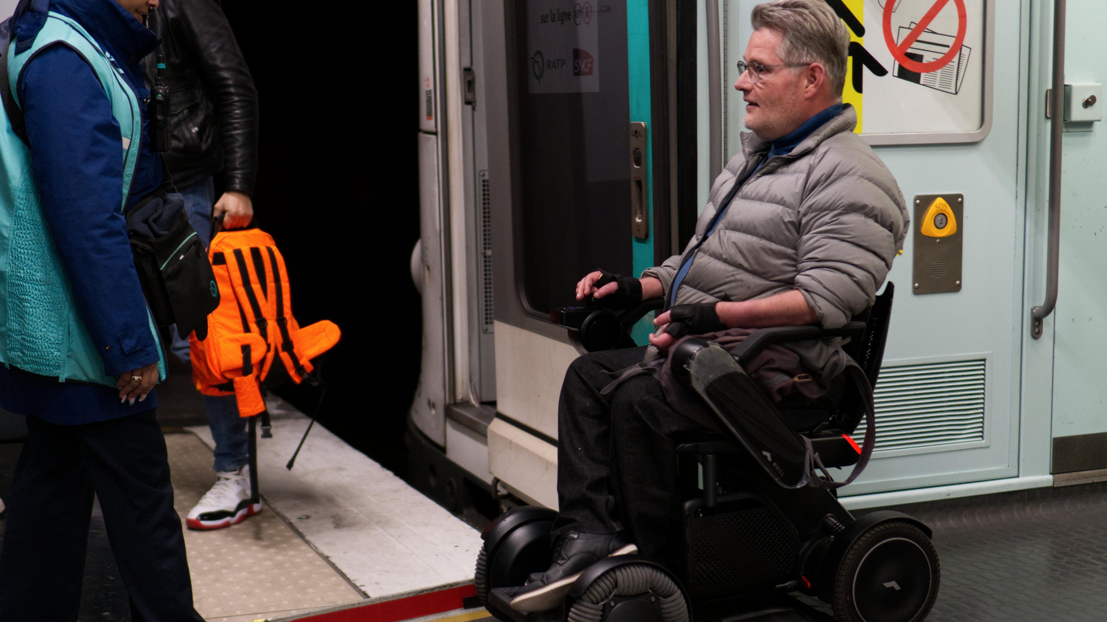 Ein Rollstuhlfahrer nutzt eine Klappe um aus einer Metro in Paris auszusteigen