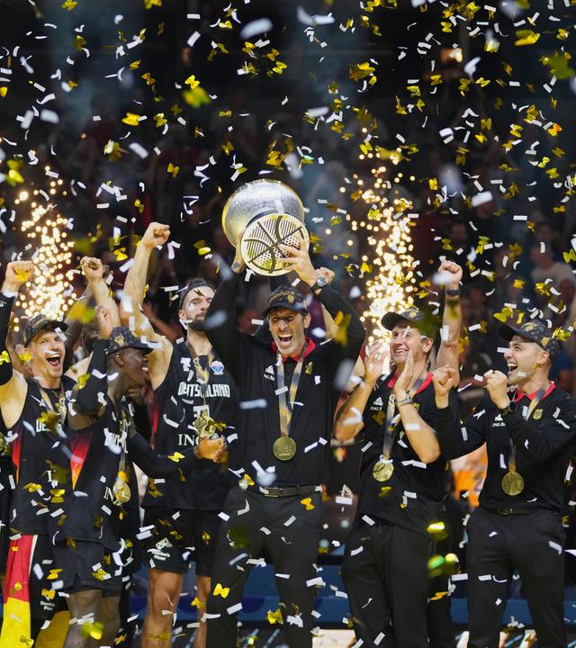 Deutschlands Cheftrainer Alex Mumbru hebt den Pokal und feiert mit seinen Spielern den EM-Sieg.