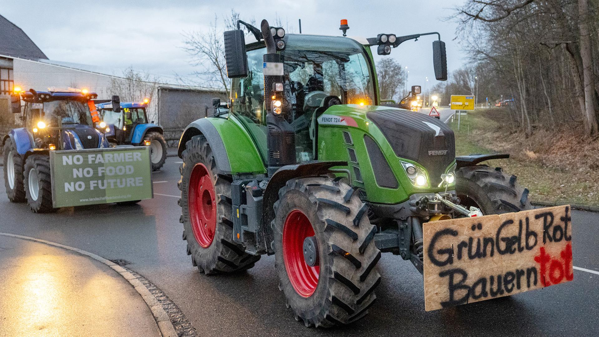 Ein großer Traktor während eines Protests von Bauern, an dessen Front ein Schild angebracht ist mit der Aufschrift: "Grün Gelb Rot. Bauern tot"
