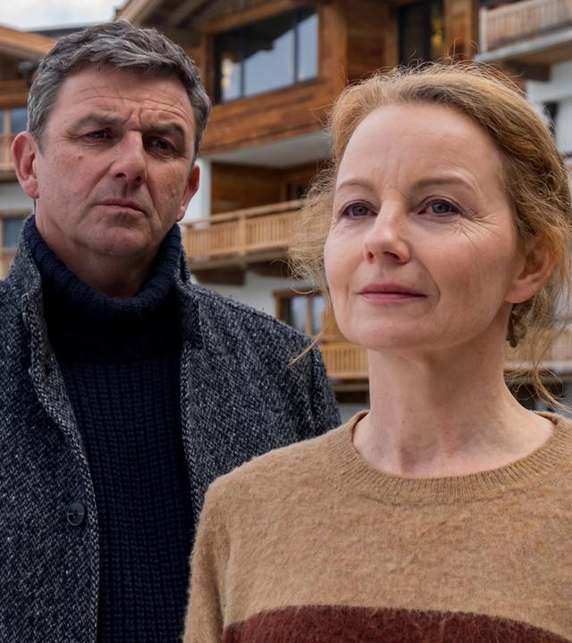 Vor einem Hotel steht Ella Kirchner (Carina Wiese) und blickt nachdenklich in die Ferne. Dr. Gruber (Hans Sigl) steht hinter ihr und blickt sie erwartungsvoll an.