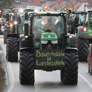 Landwirte fahren mit ihren Traktoren über die Bundesstraße 7.