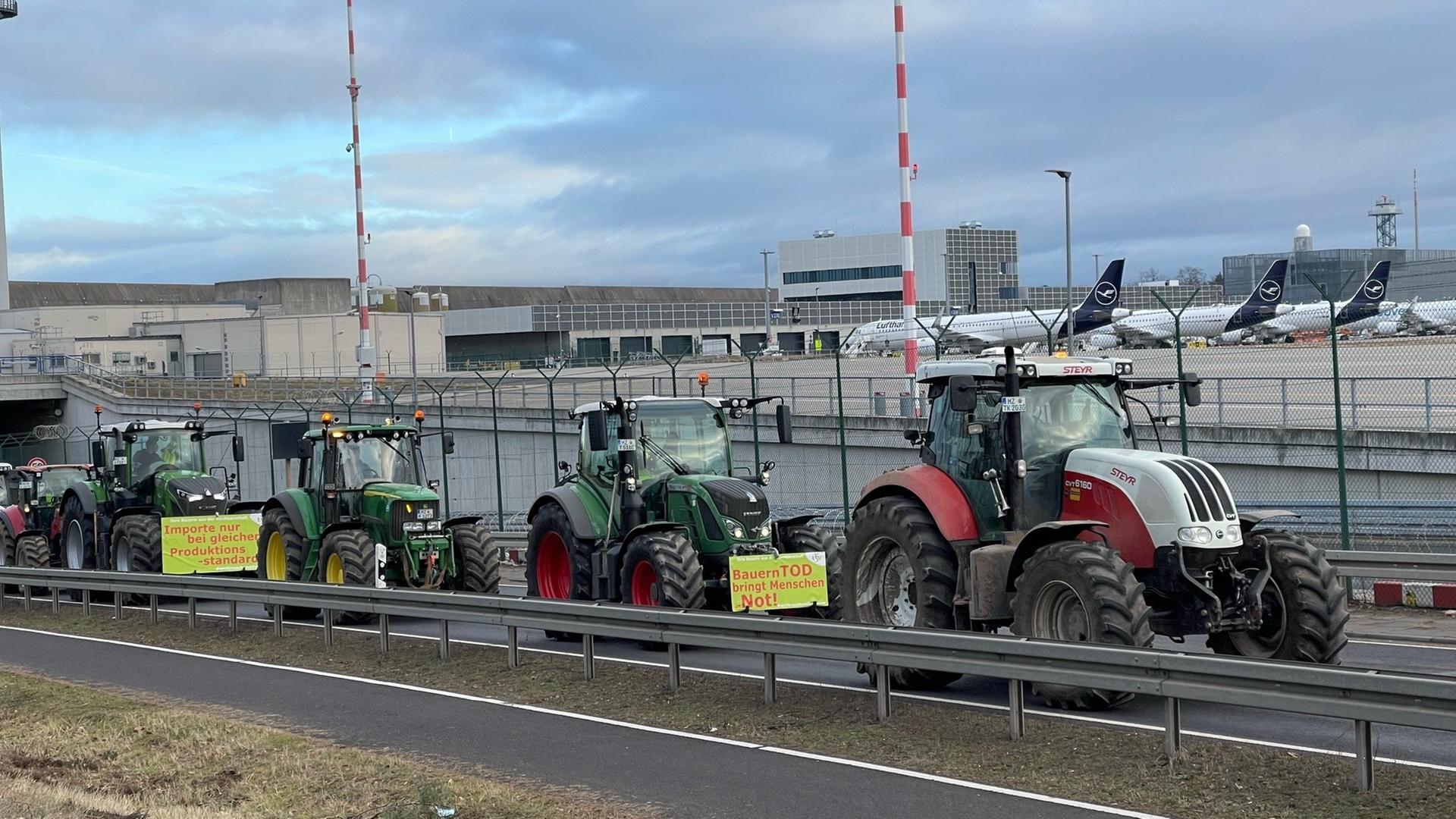 Traktoren fahren auf einer Straße am Flughafen Frankfurt vorbei
