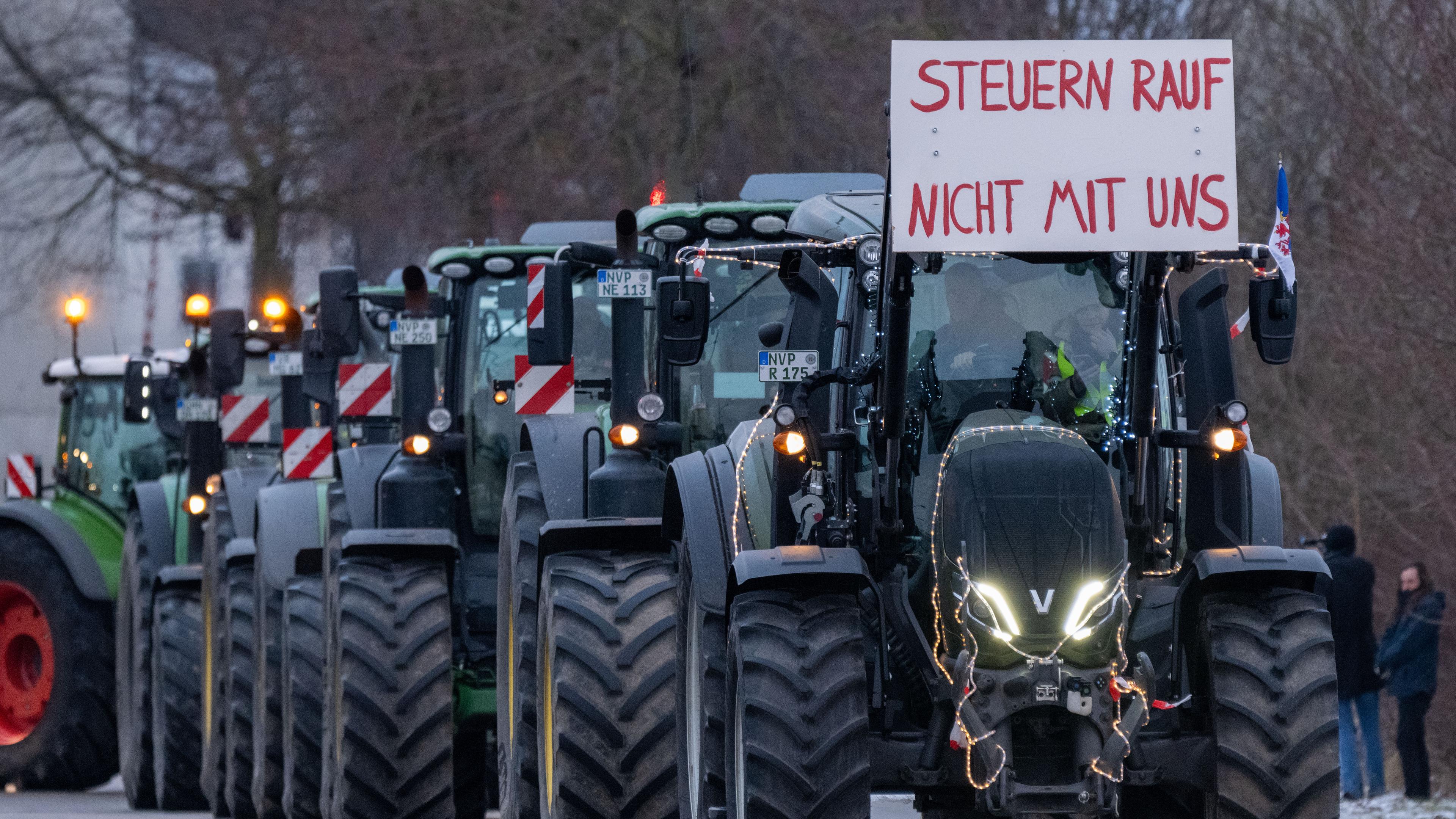 Traktoren fahren vor der Rügenbrücke auf einem Schild ist zu lesen Steuern rauf nicht mit uns